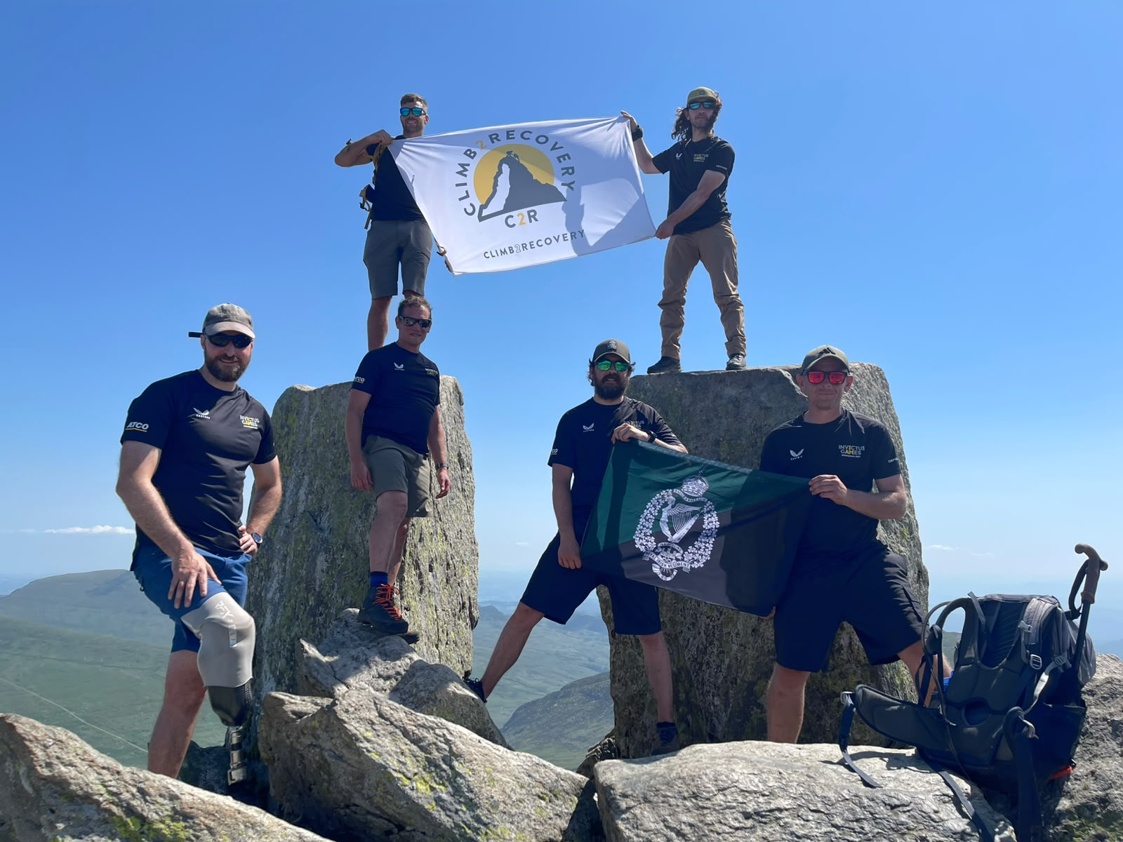 Chay Coulbert and fellow veterans holding flags on a mountain summit